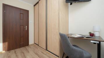 This compact room offers a relaxing atmosphere with its neatly made bed, a wall-mounted TV, and a dedicated workspace.