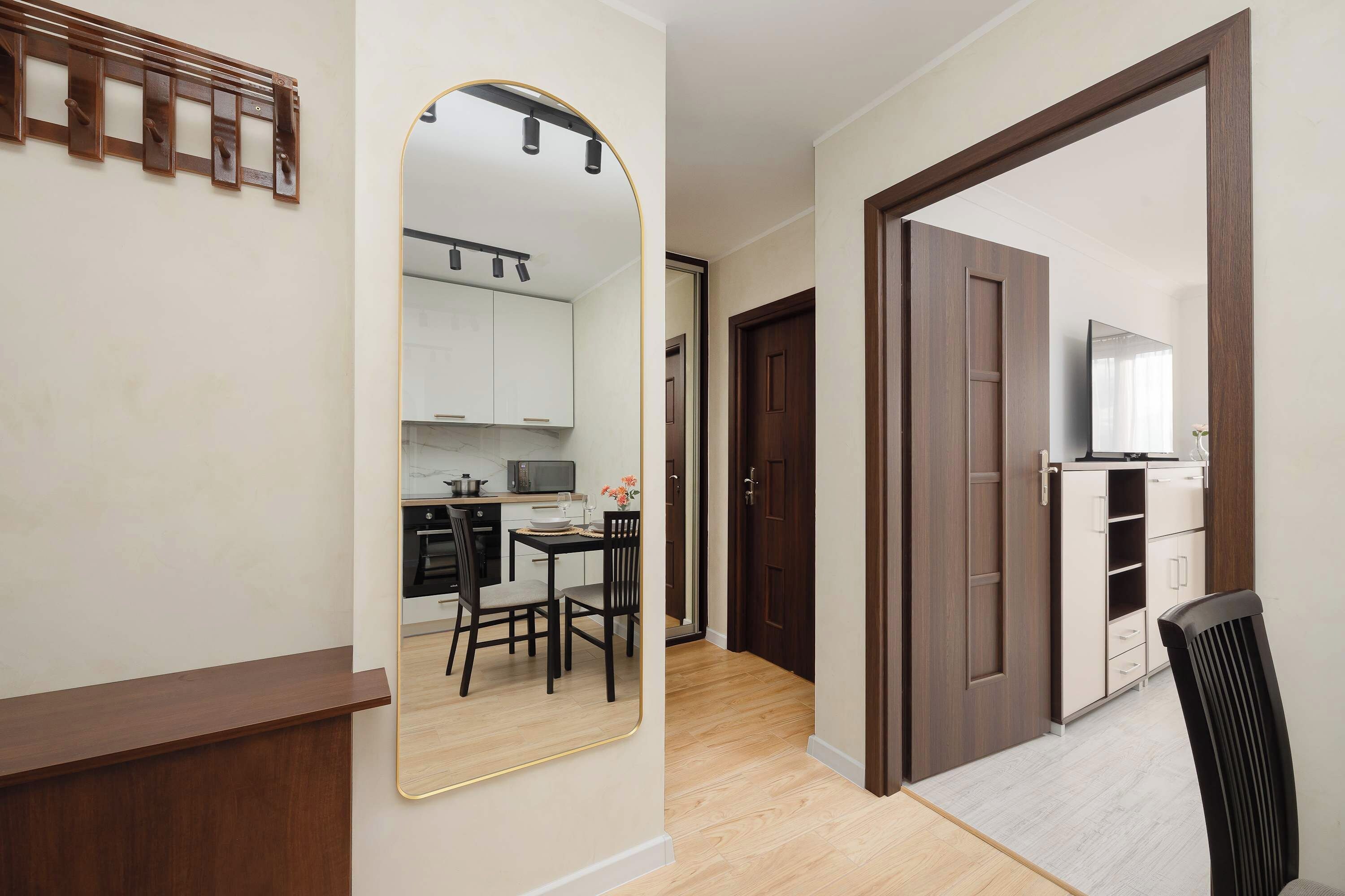 A modern kitchen with white cabinets, a microwave, and a dining area with two chairs and a table.
