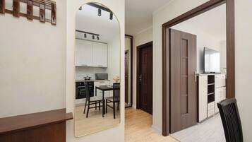 A modern kitchen with white cabinets, a microwave, and a dining area with two chairs and a table.