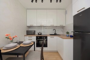 A compact kitchen with white cabinets, a microwave, a sink, and a refrigerator. - Warsaw | Przechodnia 2 | Bright Apartment | City View (Warszawa)