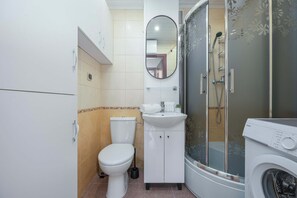 Un baño pequeño con inodoro, lavamanos y ducha.