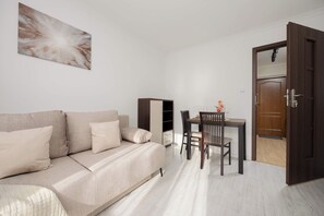 A modern living room with a sofa, a dining table with chairs, and a wardrobe. - Warsaw | Przechodnia 2 | Bright Apartment | City View (Warszawa)