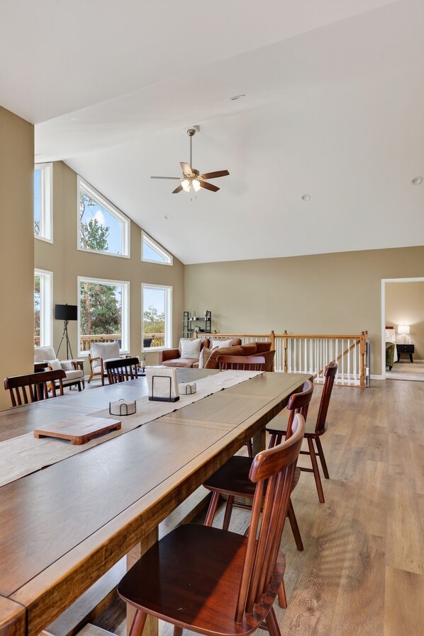 A spacious room with a long wooden table, multiple chairs, and a ceiling fan.