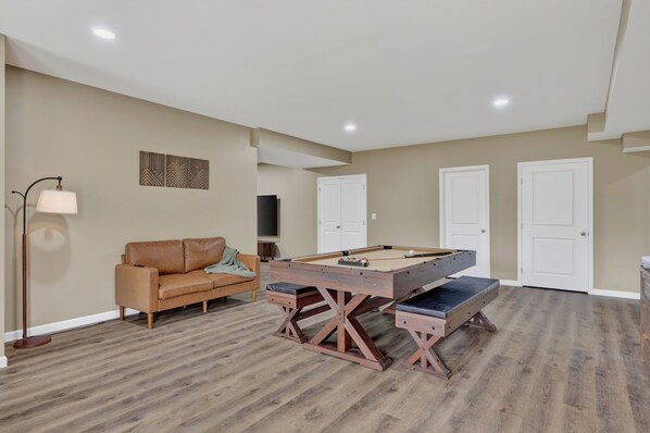 A room with a pool table, a sofa, and a television.