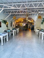 Un restaurante con una zona de bar, mesas y sillas blancas.