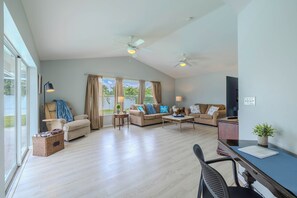 Ein geräumiges Wohnzimmer mit großem Fenster, Deckenventilator und Essbereich mit Tisch und Stühlen.