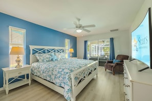 Ein Schlafzimmer mit einem Bett, einem Sessel, einem Schreibtisch und einem Fernseher, der 'Stars Vacation Rentals' anzeigt.