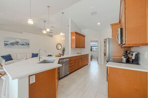 A modern kitchen with a central island, built-in appliances, and pendant lighting. - Cape Coral 3BR w/ Sun-Shelf Pool & Big Patio - Sleeps 6 (Cape Coral)