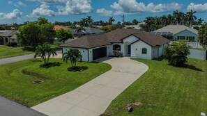 A residential house with a driveway, lawn, and a garage. - Cape Coral 3BR w/ Sun-Shelf Pool & Big Patio - Sleeps 6 (Cape Coral)