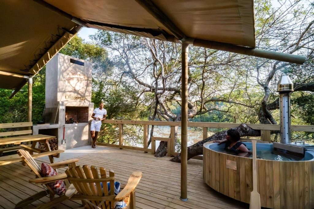 A wooden deck with outdoor seating, a barbecue grill, and a hot tub.