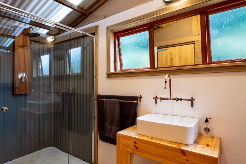 A bathroom with a wooden vanity, a white sink, and a glass shower enclosure.