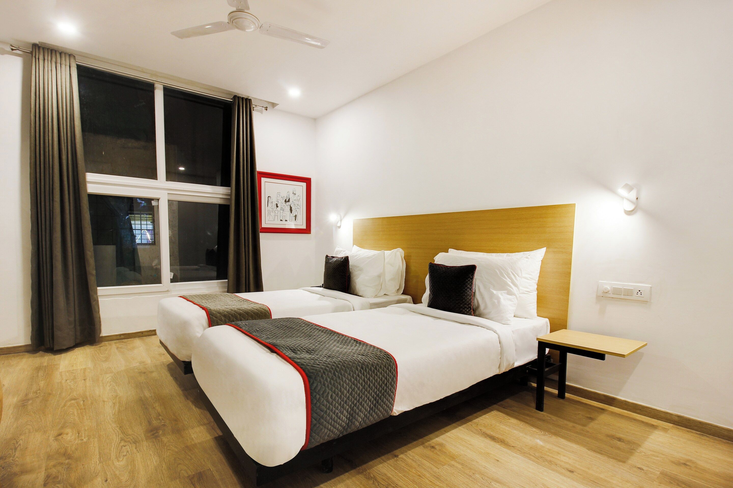 Una habitación de hotel con cama, mesitas de noche, ventana con cortinas y ventilador de techo.