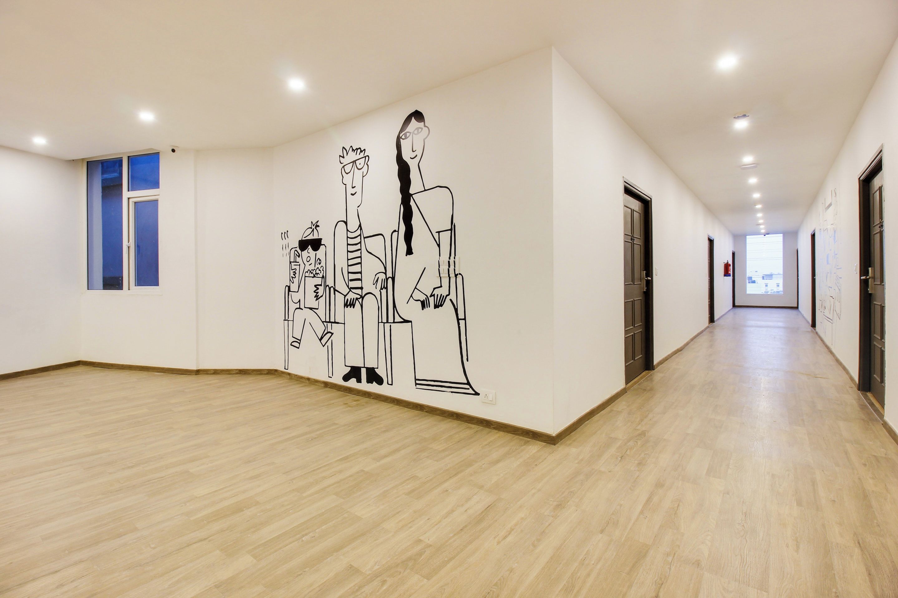 Un pasillo con piso de madera, un mural en la pared y puertas a un lado.
