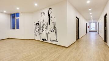 Un pasillo con piso de madera, un mural en la pared y puertas a un lado.