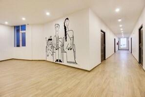 A hallway with a wooden floor, a wall mural, and doors on one side.