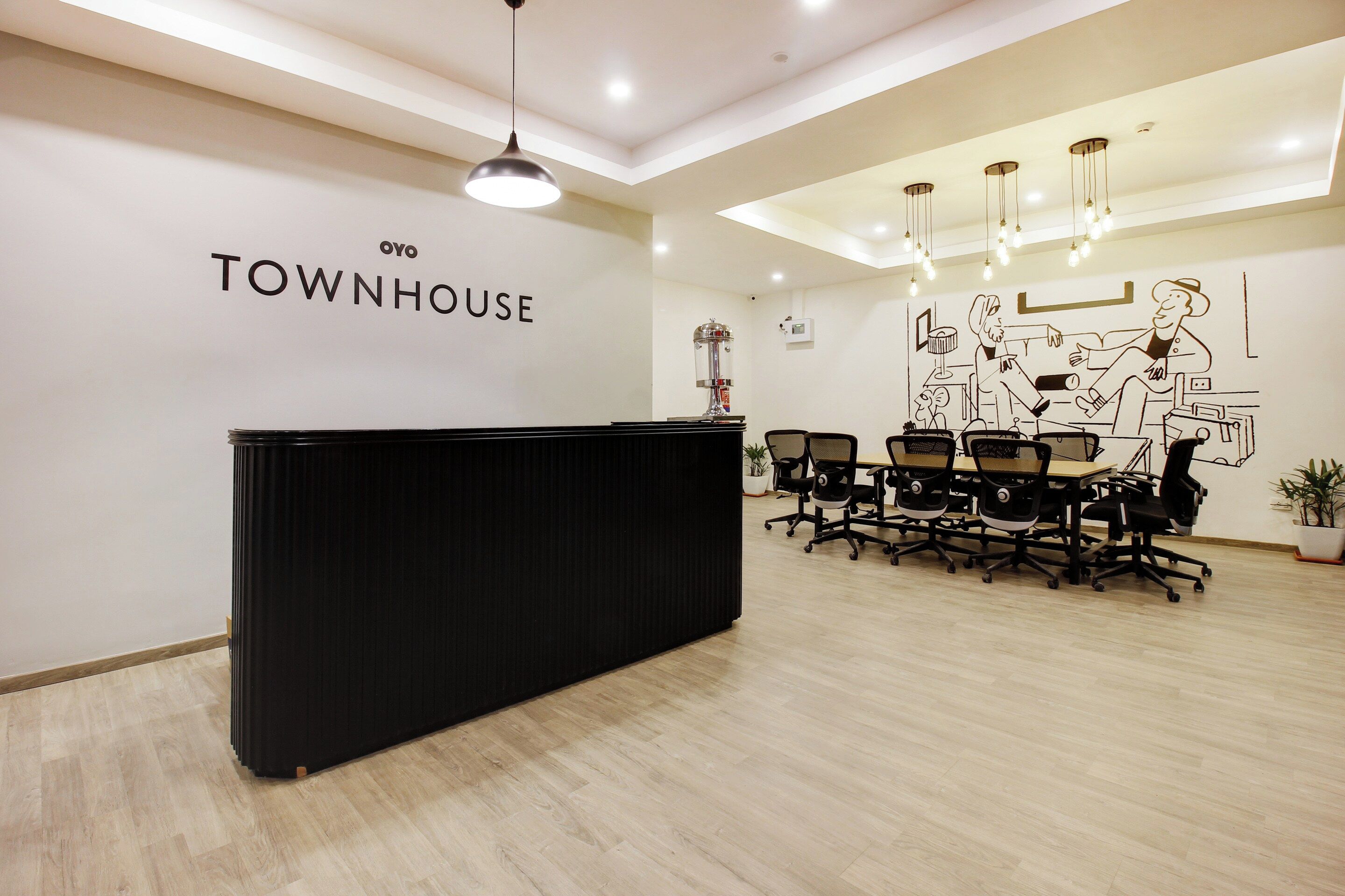 Un área de recepción con un mostrador negro, un letrero en la pared que dice 'TOWNHOUSE' y un mural grande en blanco y negro.