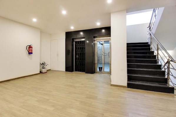 A spacious interior with a wooden floor, a staircase, and a fire extinguisher on the wall. - Super townhouse moosapet Rcc Prime (Hyderabad)