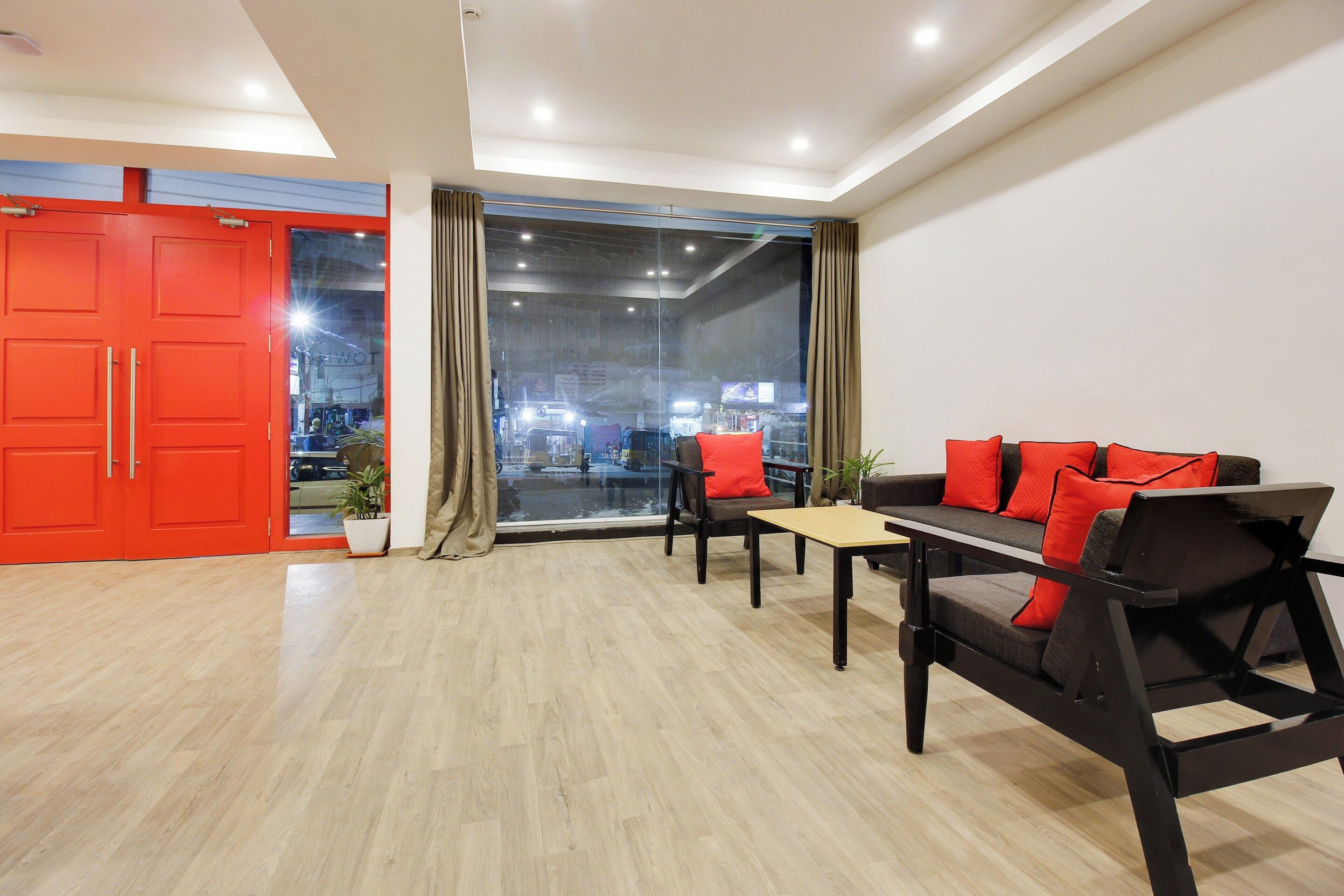 A modern living room with a sofa, a table, and a red door.
