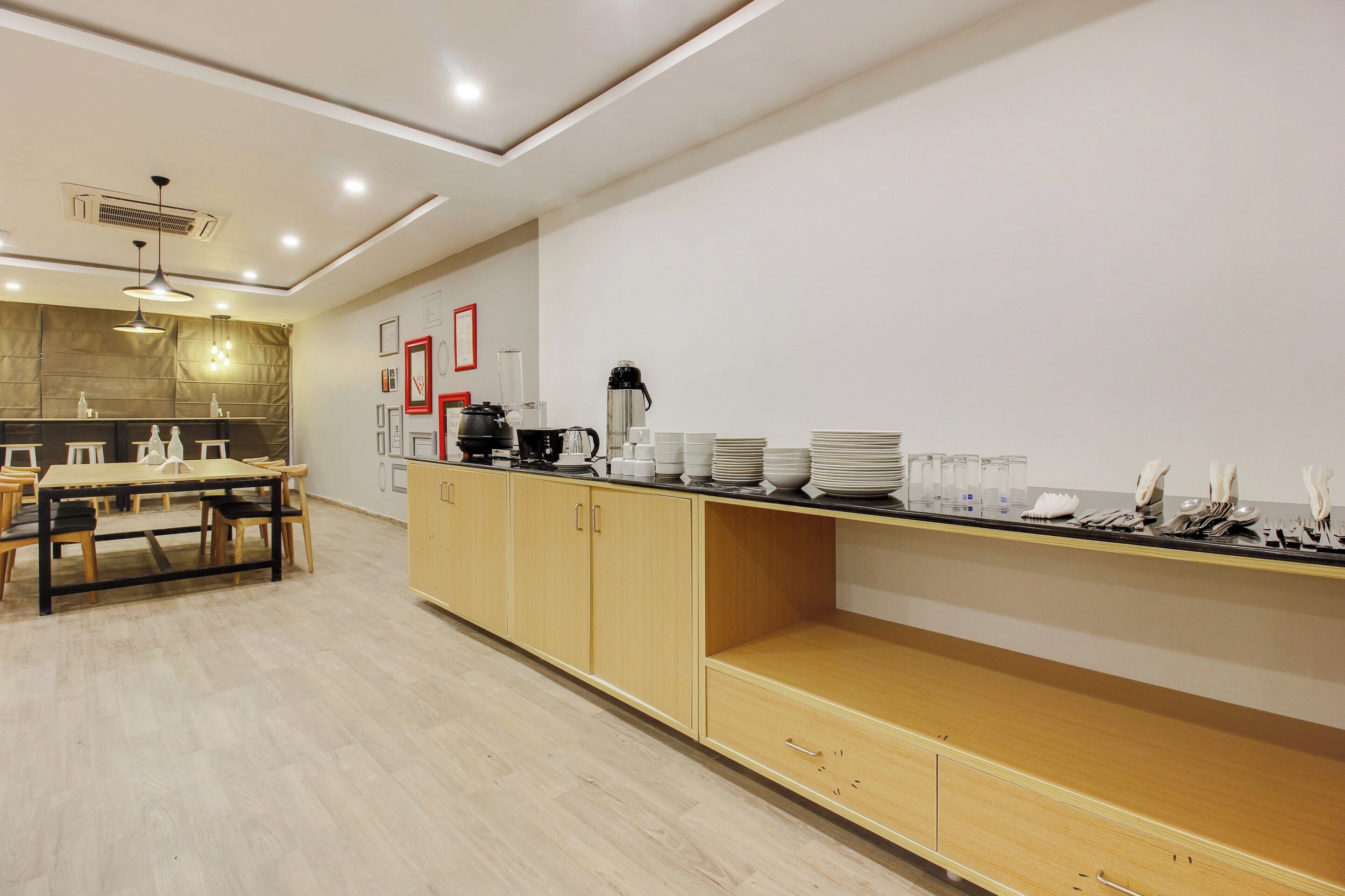 Cozinha moderna com armários de madeira, mesa de jantar e bancada com pratos e utensílios empilhados.
