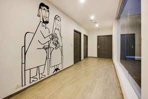 Un pasillo con un mural de dos personas, suelo de madera y puertas.