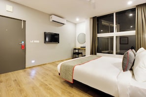 A hotel room with a bed, a television mounted on the wall, a window with curtains, and a door. - Super townhouse moosapet Rcc Prime (Hyderabad)