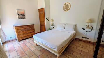 Une chambre à coucher avec un lit, une commode et une lampe fixée au mur.