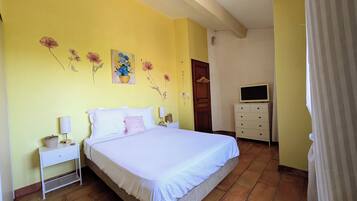 Une chambre à coucher comprenant un lit, des tables de chevet, une commode, un téléviseur et des décorations murales à motifs floraux.