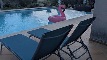 Une piscine avec des chaises longues et un flotteur en forme de flamant rose.