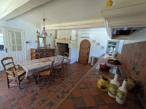 Comedor con una mesa dispuesta para cuatro personas, una araña y una chimenea.