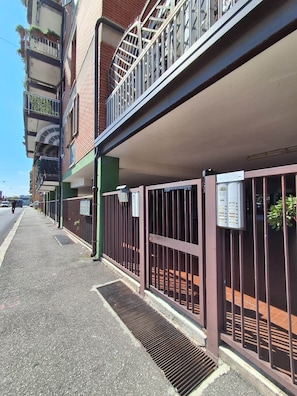 A multi-story building with a covered parking area, a gated entrance, and a visible mail slot. - Porta Fiera | Room 2 (Verona)