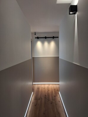 A narrow hallway with a wooden floor, white walls, and a ceiling-mounted light fixture. - Porta Fiera | Room 2 (Verona)