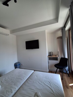 Une chambre d’hôtel avec un lit, un bureau, une chaise, une télévision et une fenêtre avec des rideaux.