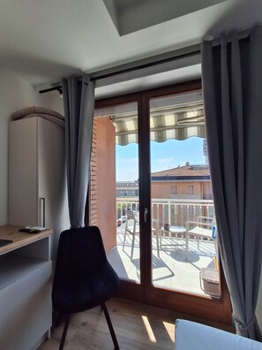 Une pièce dotée d’une porte-fenêtre coulissante donnant sur un balcon aménagé avec du mobilier d’extérieur.