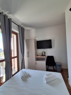 Ein Hotelzimmer mit einem Bett, einem Schreibtisch, einem Sessel, einem Fernseher und einem Fenster mit Vorhängen.