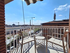 Ein Balkon mit Blick auf eine Baustelle, einen Turm und eine Straße mit Autos.