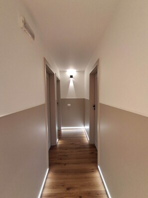 A narrow hallway with wooden flooring, white walls, and a ceiling light fixture. - Porta Fiera | Room 4 (Verona)