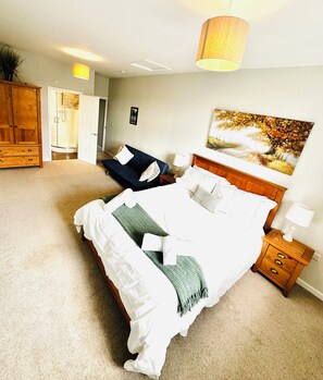 A bedroom with a bed, bedside tables, a wardrobe, and a painting on the wall. - Spacious Luxury 3 bedroom cottage with stylish interior and en-suite bathrooms (Bowness-on-Windermere)