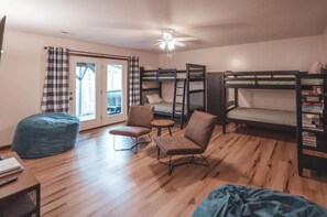 Ein Schlafsaalzimmer mit Etagenbetten, einem Schreibtisch mit Stuhl, einem Sitzsack und einem Bücherregal.