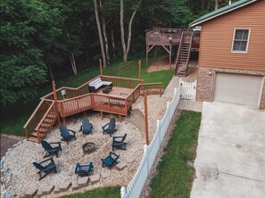 A backyard with a wooden deck, outdoor seating, and a fire pit. - Bigfoot's Hideout - Cabin-Game Room Sleeps 10 (Logan)