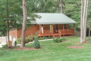 A wooden cabin with a porch, surrounded by trees and a well-maintained lawn. - Bigfoot's Hideout - Cabin-Game Room Sleeps 10 (Logan)