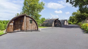 A row of rustic wooden cabins with a paved driveway leading to them.