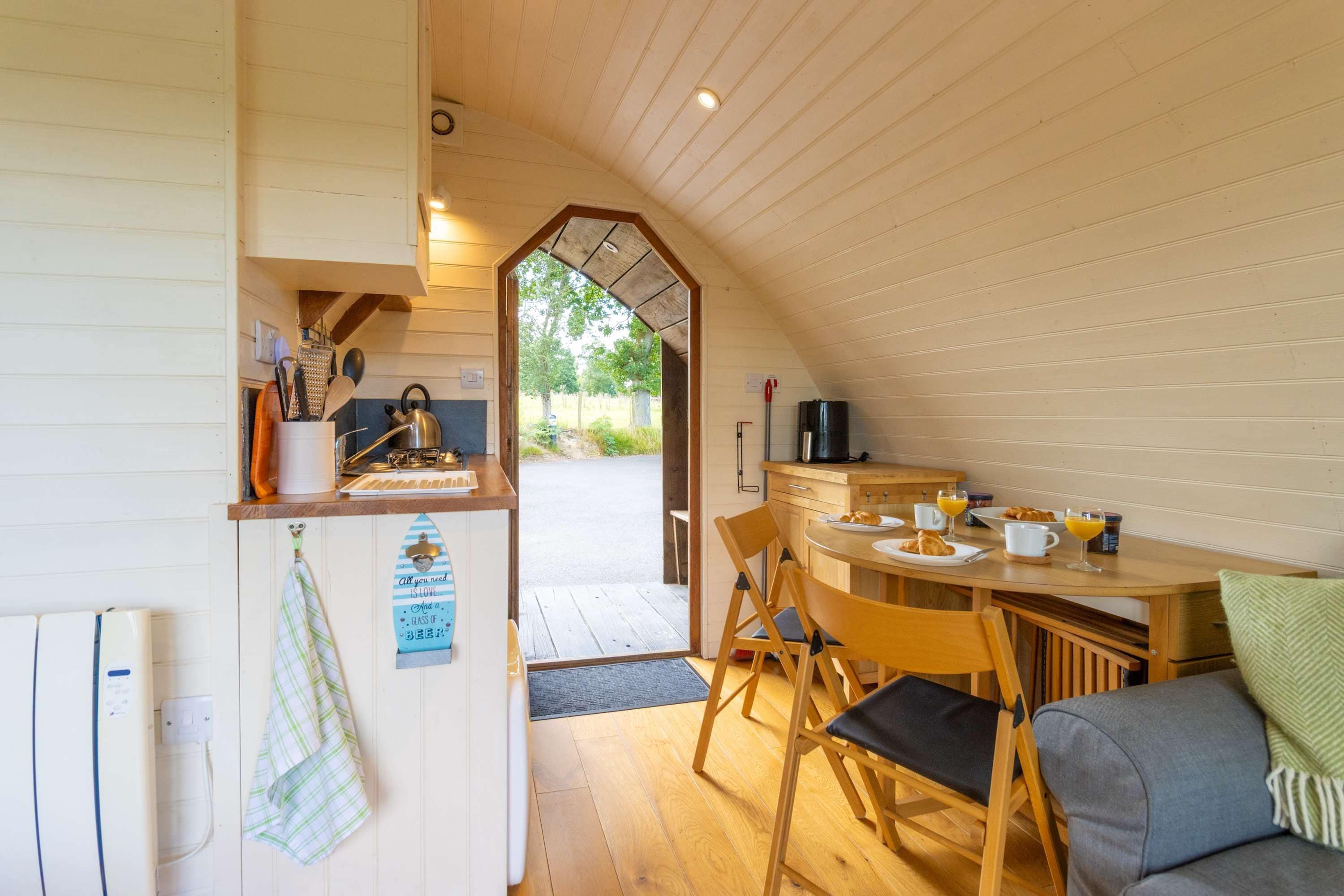 Una cocina acogedora con armarios de madera, una mesa de comedor preparada para dos personas y vistas al exterior a través de un arco.