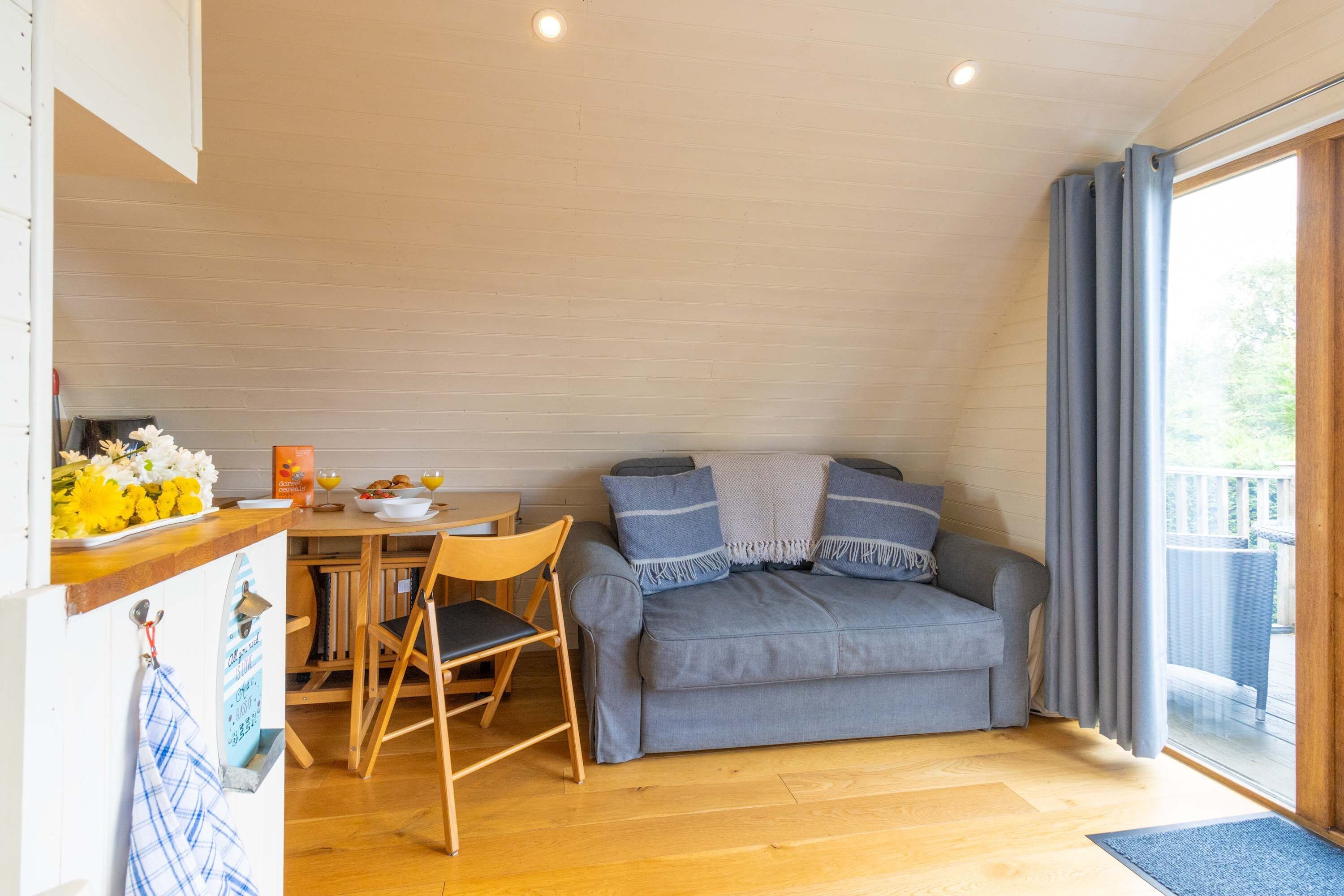 A cozy room with a dining area, a sofa, and a window with curtains.