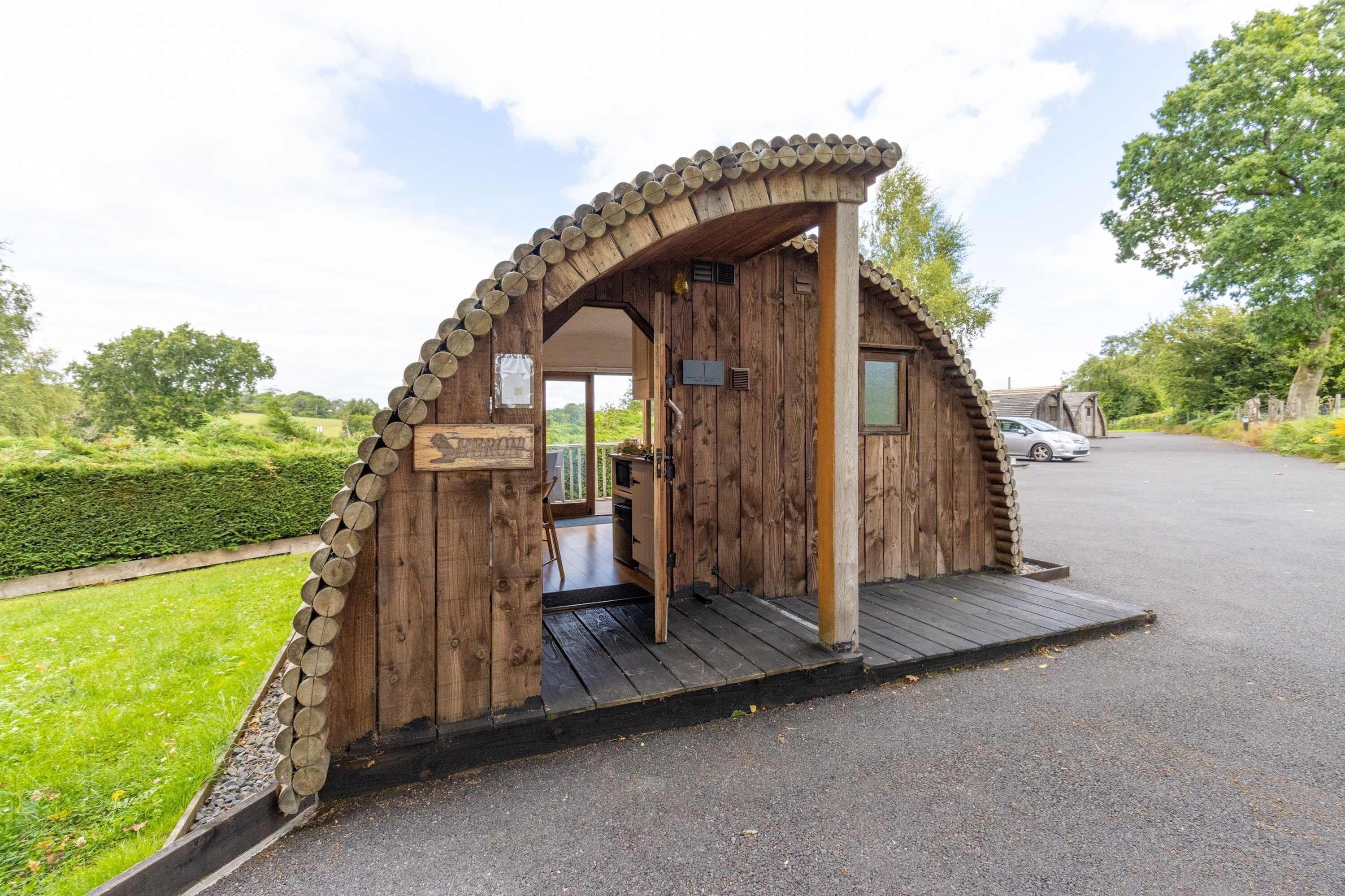 Een houten blokhut met een gebogen dak, een houten deur en een klein terras.