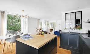 Een moderne keuken met een centraal eiland, zwarte kasten en een eethoek met een tafel en stoelen.