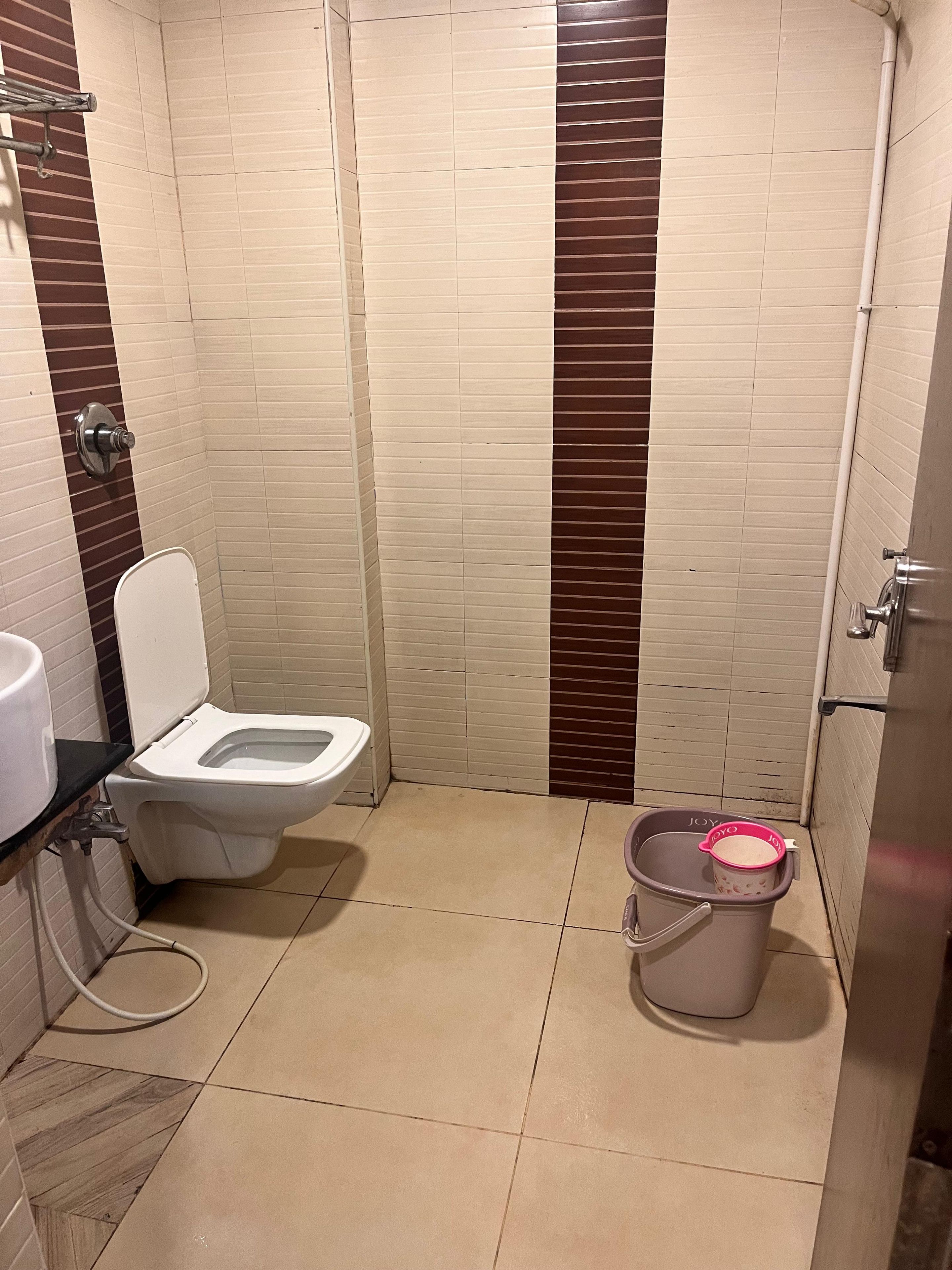 A small bathroom with a toilet, a sink, and a trash bin.