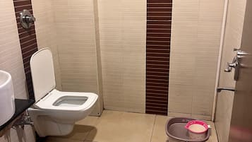A small bathroom with a toilet, a sink, and a trash bin.