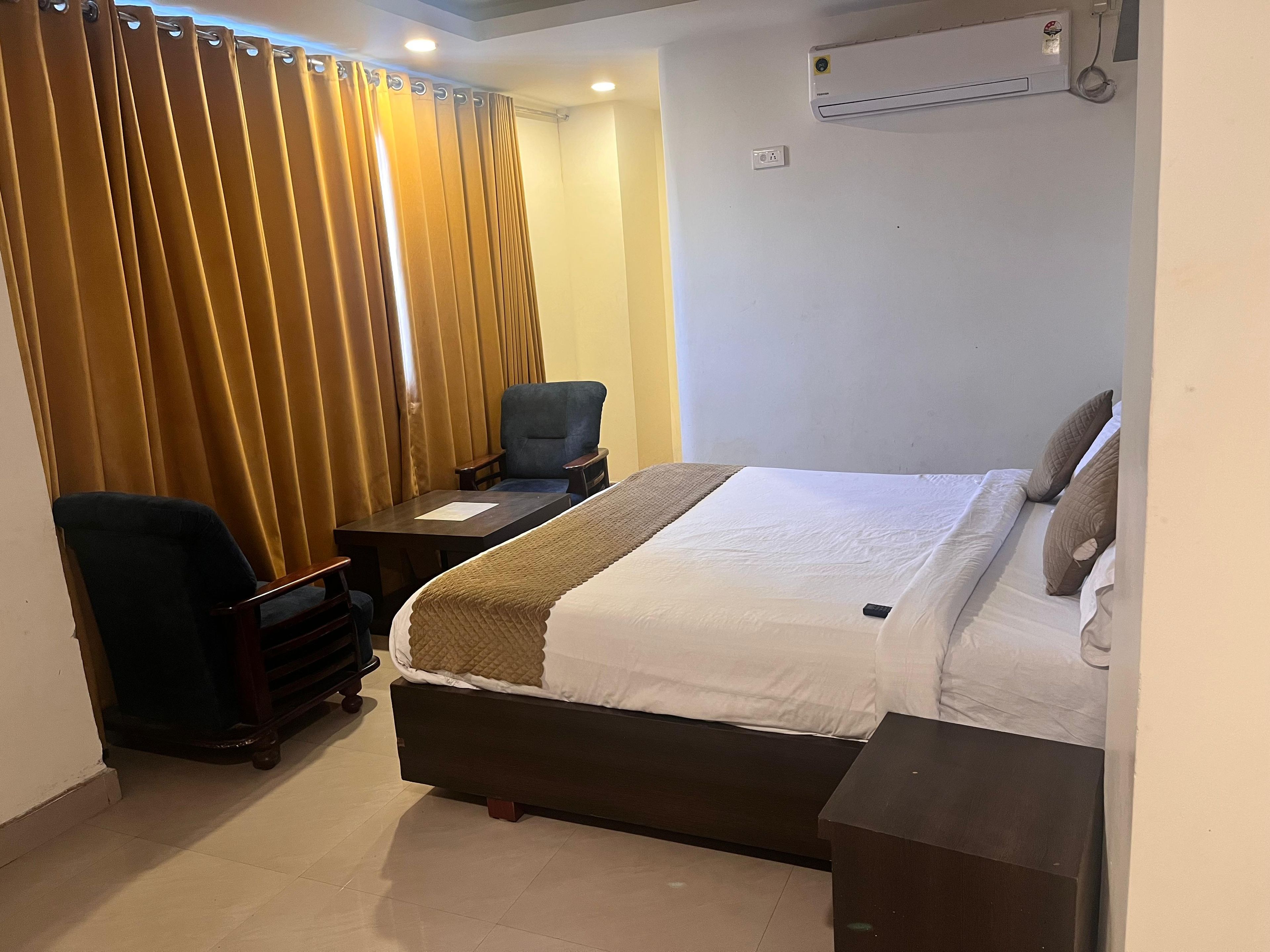 Ein Hotelzimmer mit einem Bett, einem Schreibtisch, einem Stuhl und einem Vorhang.