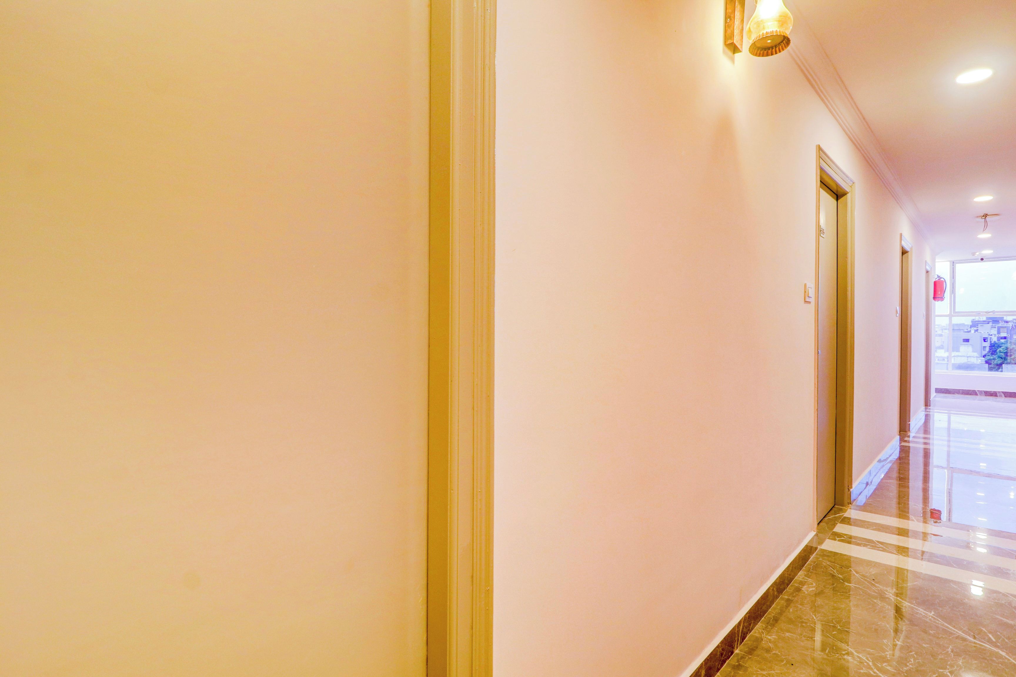 A hotel corridor with a marble floor, doors on the right, and a light fixture above.