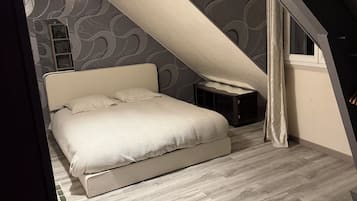 Ein Schlafzimmer mit einem Bett, einem Nachttisch, einer Pendelleuchte und einem Fenster mit Vorhängen.